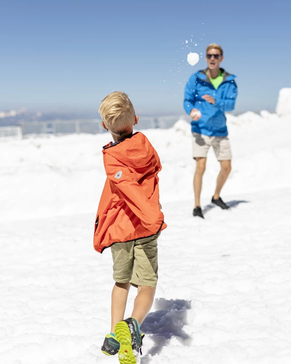 Familie spielt an einem Sommertag auf dem Gletscher Schneeball